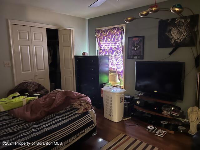 bedroom with ceiling fan, a closet, and dark wood-type flooring