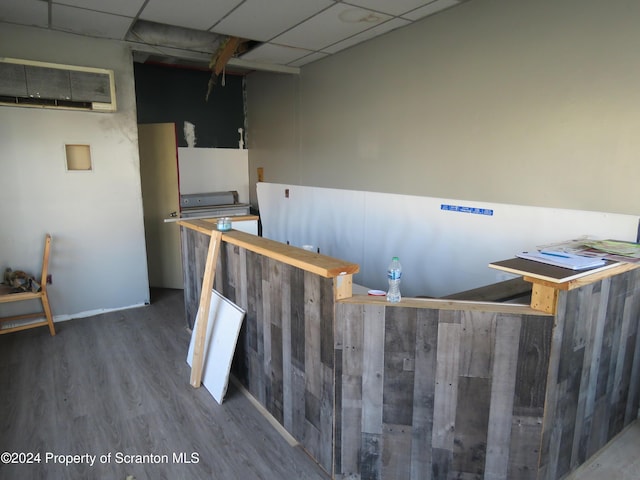 kitchen featuring hardwood / wood-style floors, a wall unit AC, and a drop ceiling