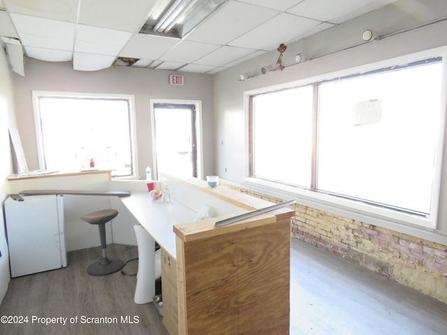 kitchen with a paneled ceiling, a breakfast bar, kitchen peninsula, and light hardwood / wood-style flooring