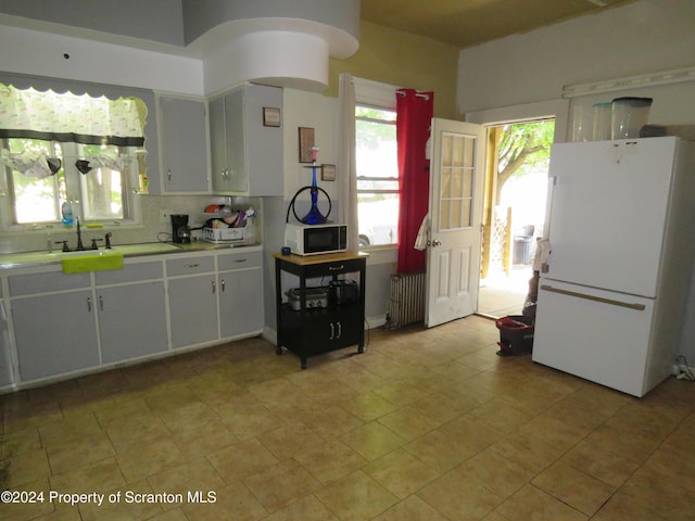 kitchen featuring white cabinetry, white appliances, sink, and radiator