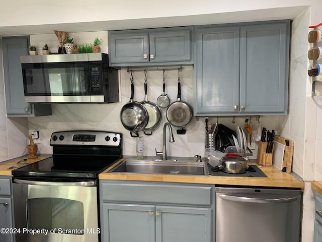 kitchen with backsplash, gray cabinets, sink, and appliances with stainless steel finishes