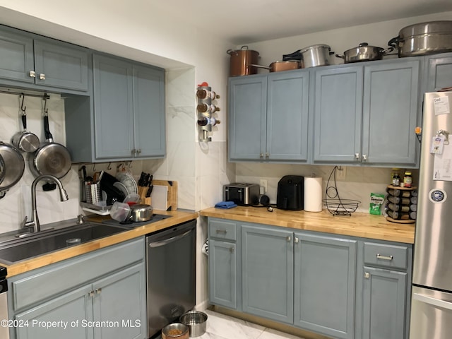 kitchen with tasteful backsplash, butcher block counters, sink, and appliances with stainless steel finishes