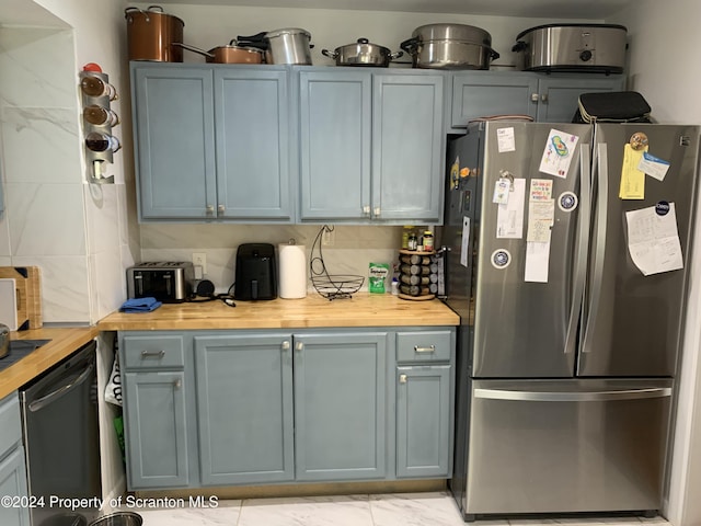 kitchen with butcher block countertops, appliances with stainless steel finishes, and tasteful backsplash