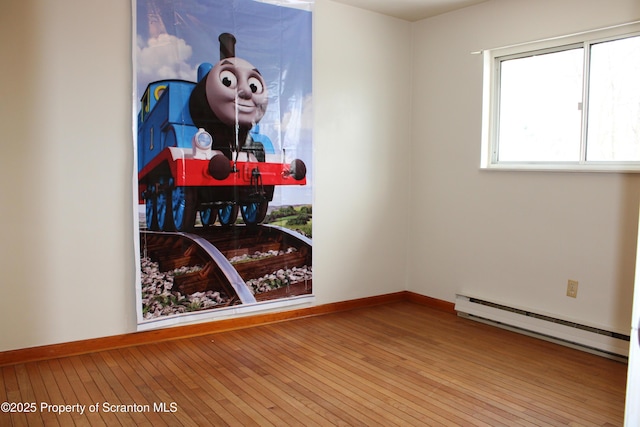 empty room with light hardwood / wood-style flooring and a baseboard heating unit