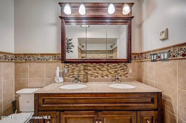 bathroom featuring tile walls, vanity, and toilet