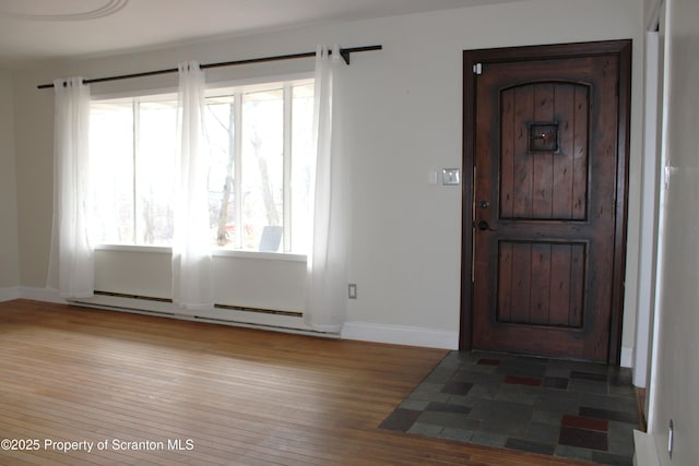 entrance foyer with a baseboard heating unit, a wealth of natural light, and hardwood / wood-style floors