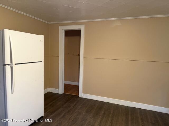 spare room with crown molding, baseboards, and dark wood-type flooring