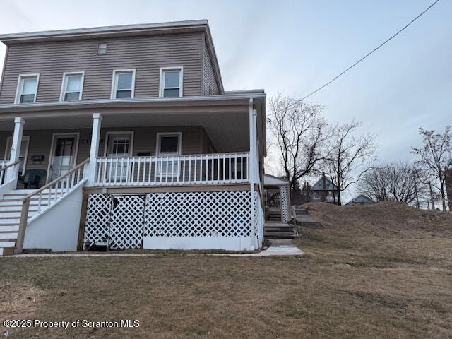 view of front of house featuring a porch, stairway, and a front yard