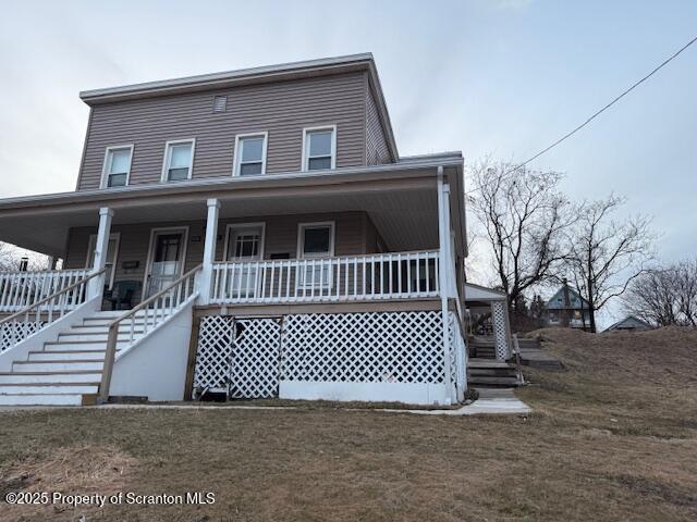 view of front of home with stairs, a front lawn, and a porch