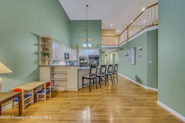 33 Hedge Row Run, Clarks Summit, PA 18411 - kitchen with open shelves, a towering ceiling, black appliances, light wood-type flooring, and a breakfast bar area