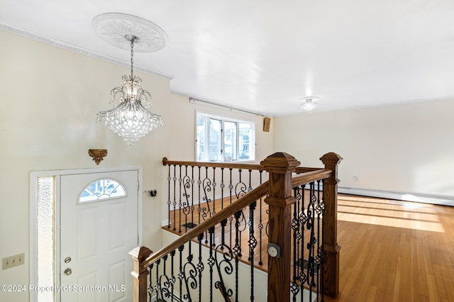 stairs featuring baseboard heating, hardwood / wood-style floors, and a chandelier