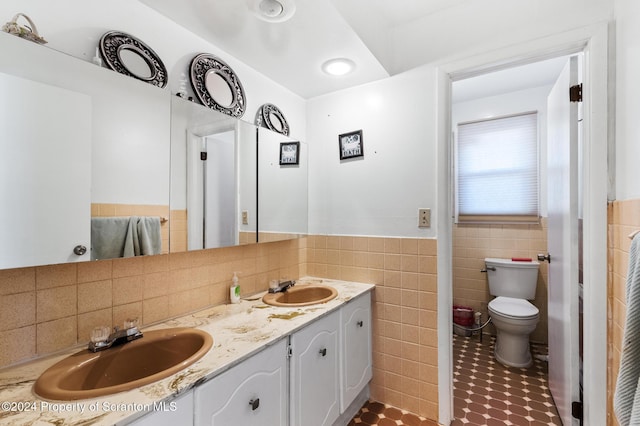 bathroom featuring vanity, toilet, and tile walls