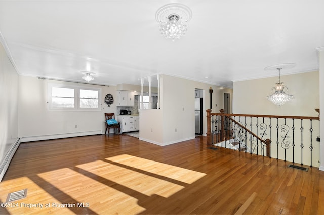 unfurnished living room featuring hardwood / wood-style flooring, ornamental molding, and a notable chandelier