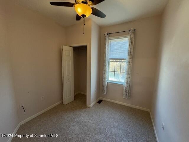 unfurnished bedroom featuring ceiling fan, light colored carpet, a walk in closet, and a closet