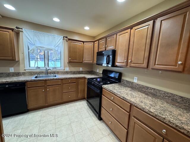 kitchen featuring black appliances, dark stone countertops, and sink