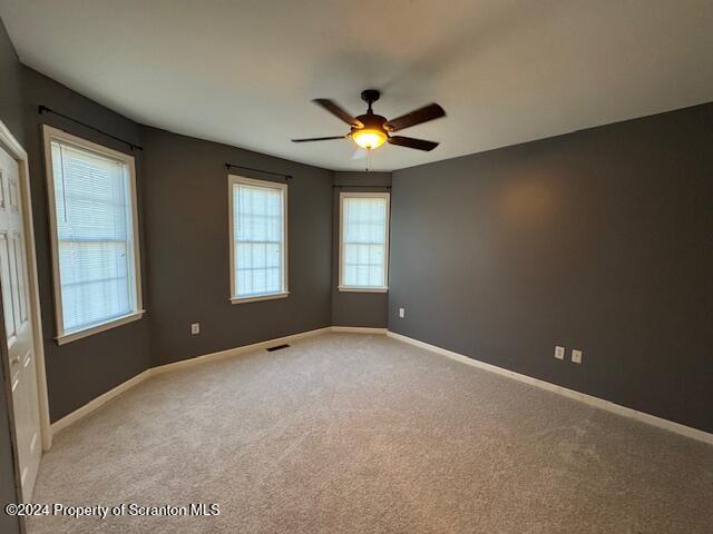 carpeted spare room featuring ceiling fan