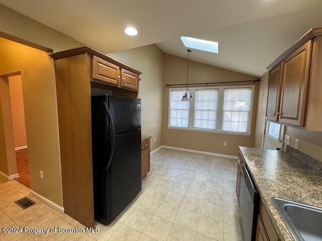 kitchen with black fridge, dishwasher, sink, and vaulted ceiling with skylight