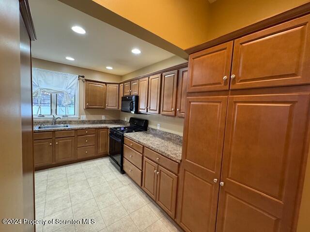 kitchen featuring sink, black appliances, and stone countertops