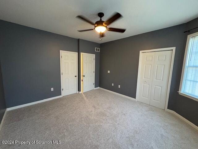 unfurnished bedroom featuring multiple windows, light carpet, and ceiling fan