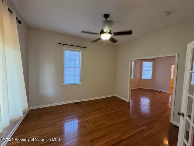 empty room featuring ceiling fan and dark wood-type flooring