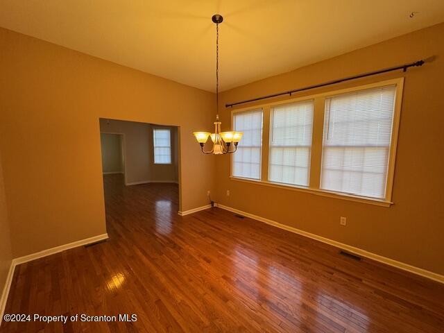 unfurnished dining area featuring dark wood-type flooring and a notable chandelier