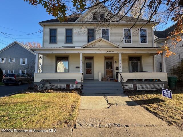 front facade with a porch and a front yard