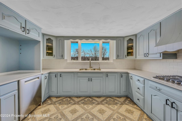 kitchen with decorative backsplash, sink, stainless steel appliances, and range hood