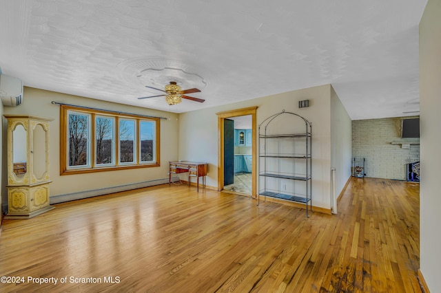 interior space with a fireplace, ceiling fan, light hardwood / wood-style flooring, and a baseboard heating unit