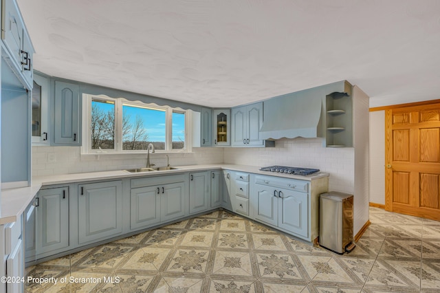 kitchen with premium range hood, stainless steel gas cooktop, tasteful backsplash, and sink