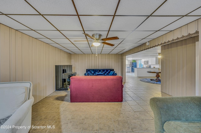 living room featuring light tile patterned floors, a drop ceiling, and ceiling fan