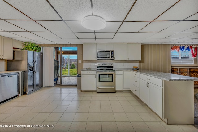 kitchen featuring white cabinetry, light stone countertops, a drop ceiling, and appliances with stainless steel finishes