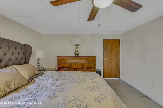 bedroom with ceiling fan, a drop ceiling, and light tile patterned floors