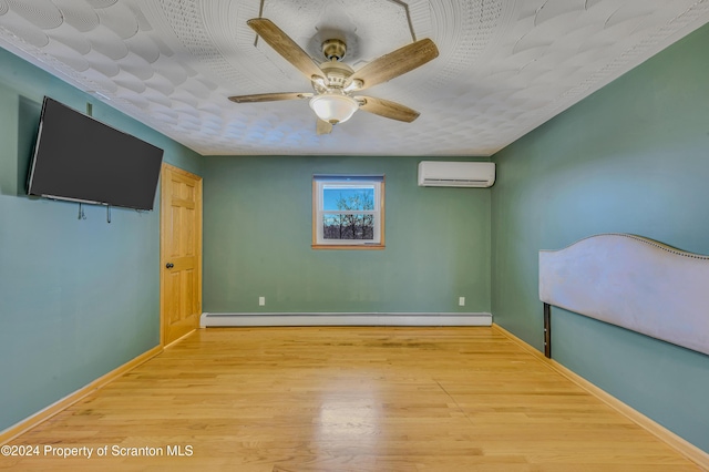 unfurnished bedroom featuring a textured ceiling, a wall unit AC, ceiling fan, a baseboard heating unit, and wood-type flooring