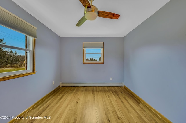 spare room featuring ceiling fan, a baseboard heating unit, and light hardwood / wood-style flooring