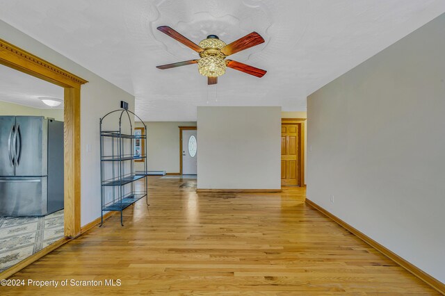 unfurnished living room with light hardwood / wood-style floors, ceiling fan, and a baseboard heating unit