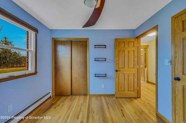 unfurnished bedroom featuring a baseboard radiator, a closet, light hardwood / wood-style floors, and ceiling fan