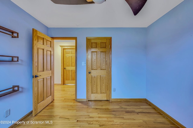 unfurnished bedroom with ceiling fan and light wood-type flooring