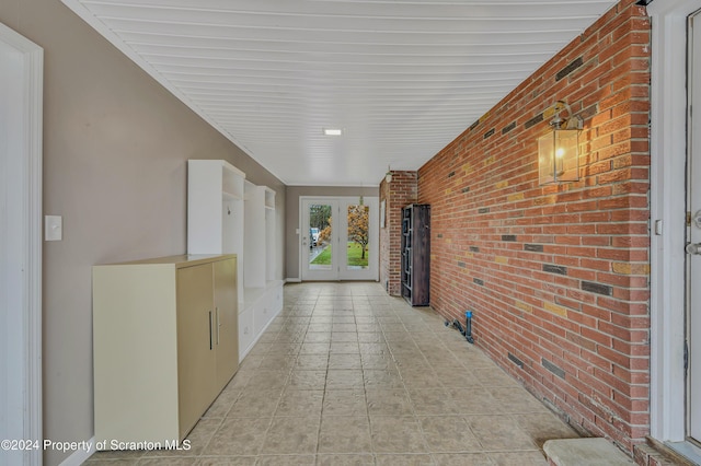 hall featuring french doors and brick wall