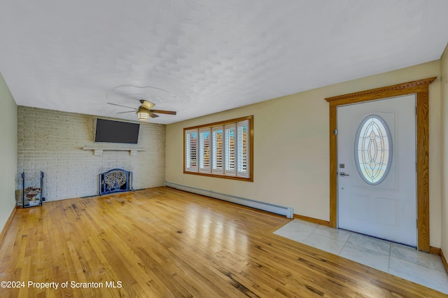 foyer entrance with brick wall, plenty of natural light, a baseboard heating unit, and ceiling fan