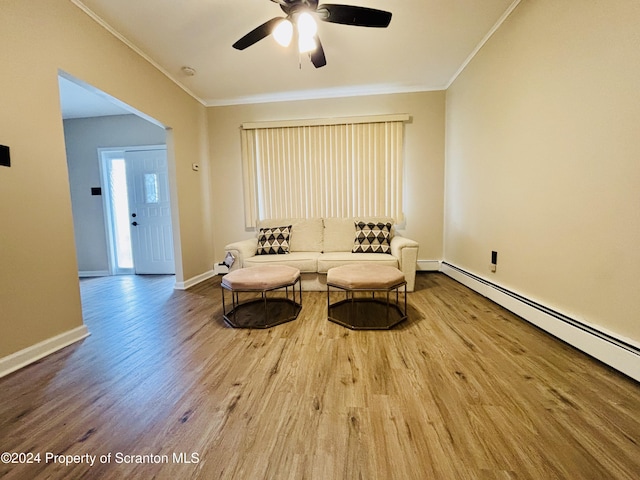 living area with hardwood / wood-style flooring, a baseboard radiator, ceiling fan, and crown molding