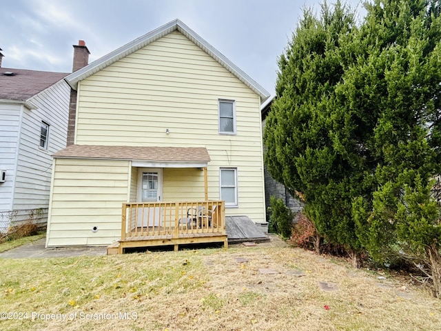 rear view of house with a lawn and a wooden deck