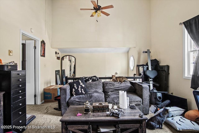 living room featuring light carpet, ceiling fan, and a high ceiling