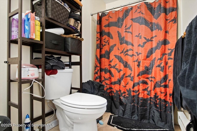 bathroom with a baseboard heating unit, a shower with shower curtain, and toilet