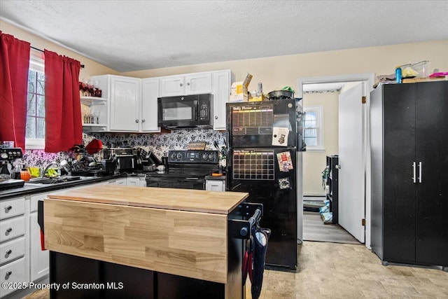 kitchen featuring white cabinetry, butcher block countertops, sink, and black appliances