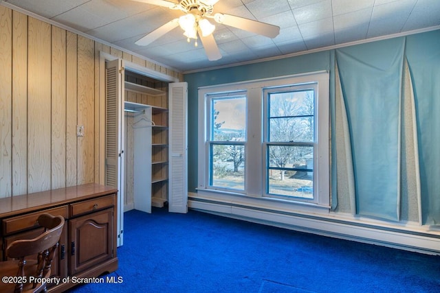 unfurnished bedroom with a baseboard heating unit, dark colored carpet, and ornamental molding