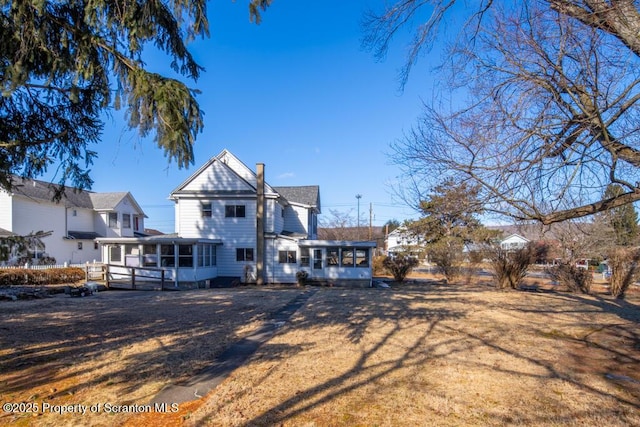 rear view of property with a sunroom and a lawn