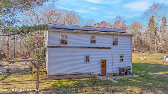 back of house featuring solar panels and a lawn