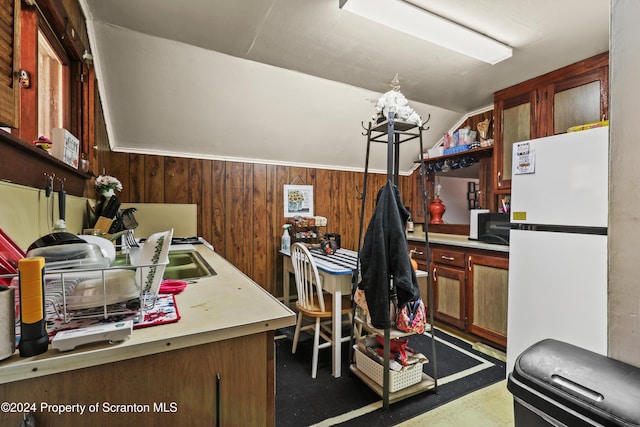 kitchen with white refrigerator, lofted ceiling, and wooden walls