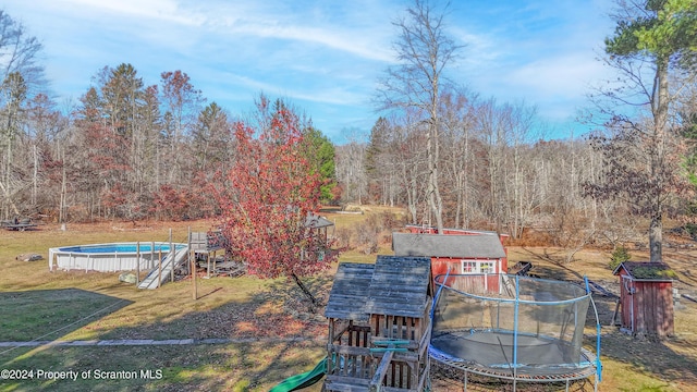 view of yard featuring an outdoor structure and a trampoline