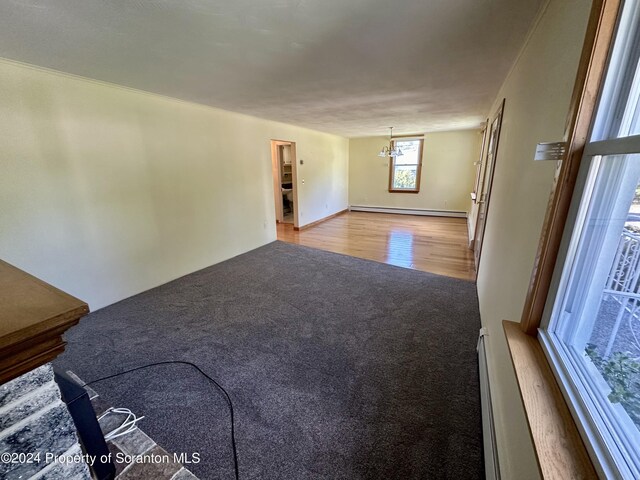 1402 Cherry St, Scranton, PA 18505 - unfurnished living room featuring carpet, a baseboard heating unit, a chandelier, and wood finished floors